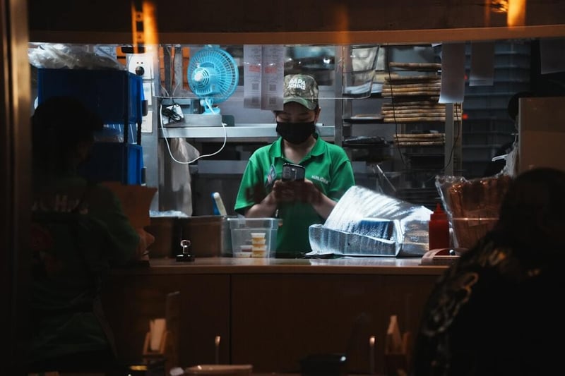Worker in green shirt prepares food at counter