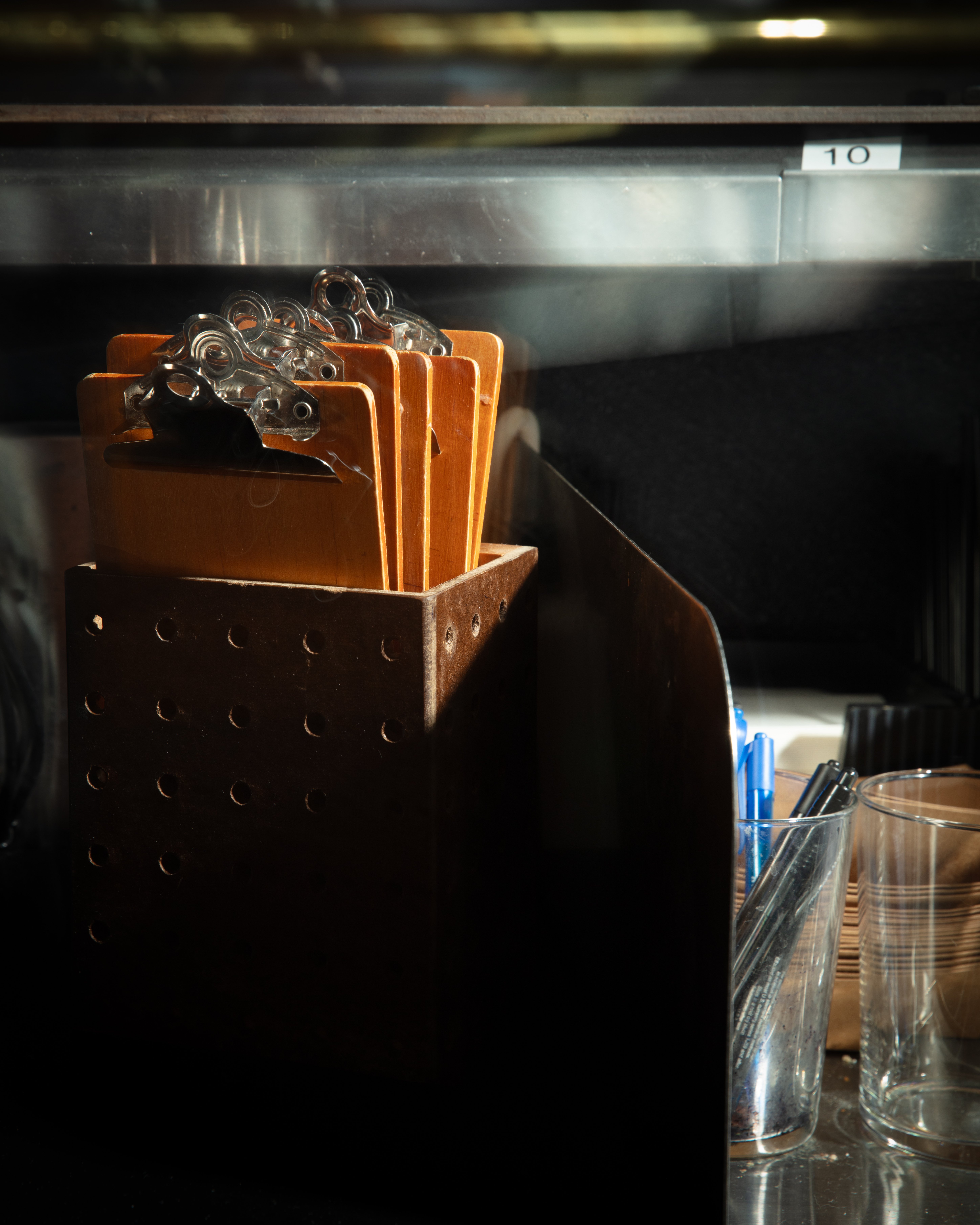 Small clipboards in a wooden container on a counter